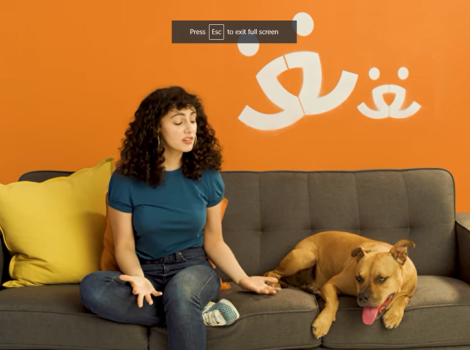 Screen shot of woman talking to a dog, with them both on a couch and a Best Friends logo behind them